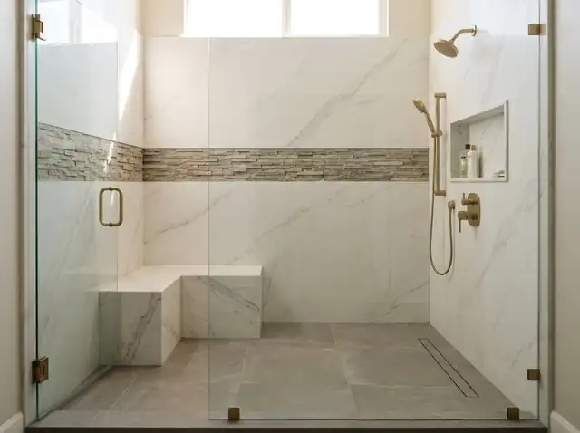 Walk-in shower with white veined stone walls, a stone bench and a frameless glass door (illustration)