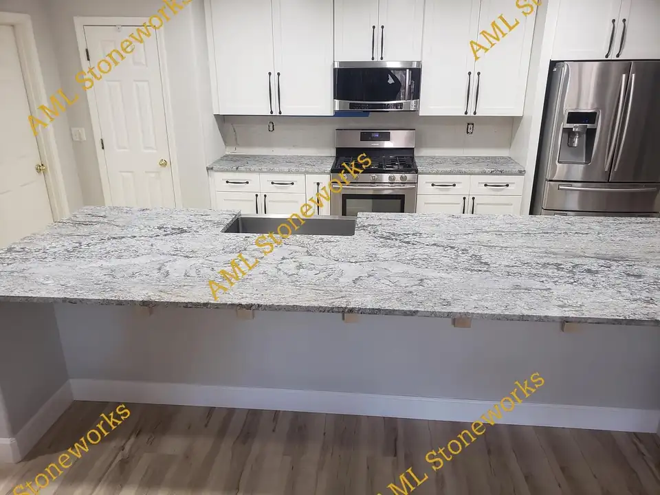 Countertop installation in the Central Valley: long gray and white granite island with an undermount sink in a white shaker kitchen