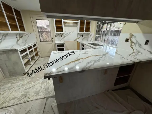 White stone with bold gold and gray veining on a kitchen counter and backsplash during installation