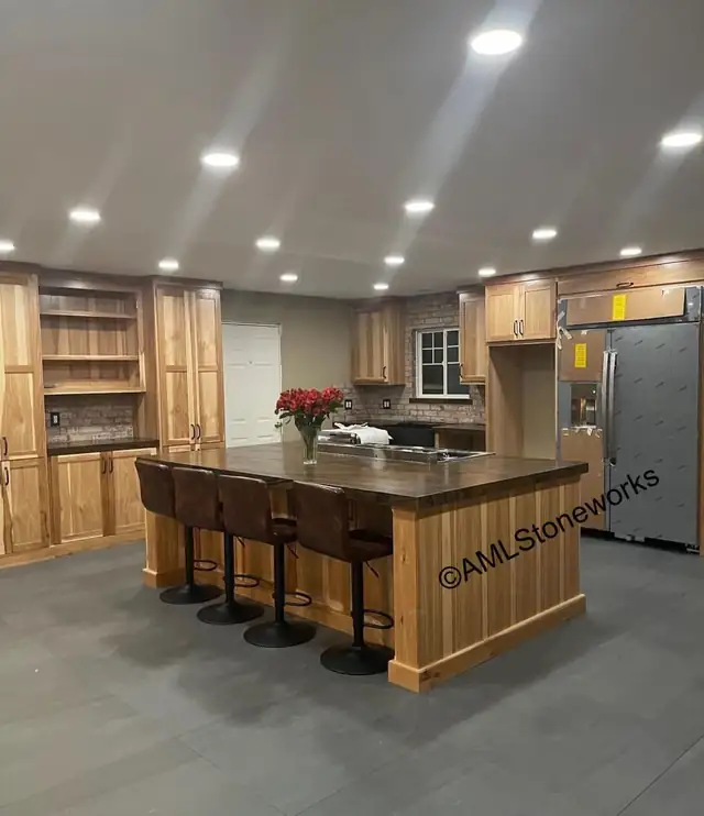 Large kitchen with natural wood cabinets and a big island with a dark stone top and four bar stools
